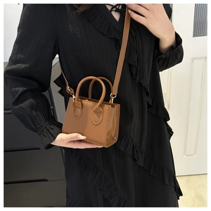 Detail of caramel brown mini tote bag with matte leather finish and gold hardware accents