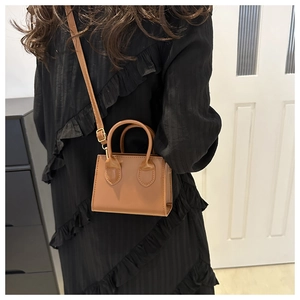 Close-up of a brown mini crossbody bag with gold hardware and adjustable strap detail