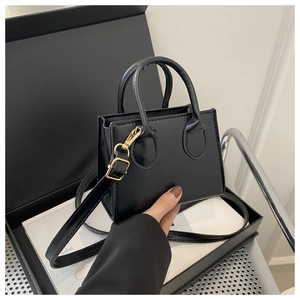 Detail of glossy black mini tote bag with gold hardware and adjustable strap