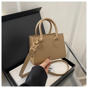 Close-up of khaki mini handbag with dual handles, gold hardware, and adjustable strap