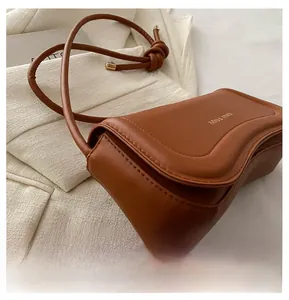 Detail of matte brown leather bag with gold Miss Mini branding and knot strap design