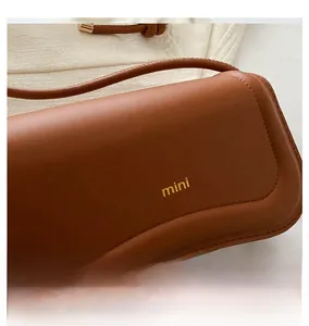 Close-up of brown leather mini shoulder bag with gold Miss mini lettering detail