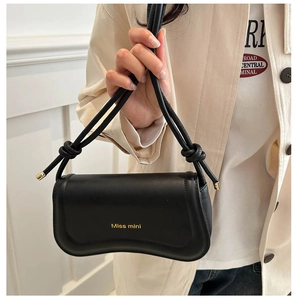 Detail of knot shoulder strap with gold metal ends on a black minimalist shoulder bag