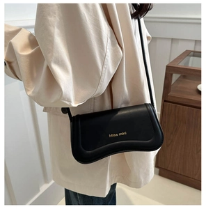 Detail of black underarm bag featuring gold Miss Mini text and sleek curved silhouette