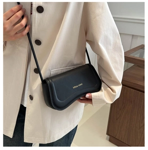 Detail of a chic black leather underarm bag with gold Miss mini logo on a shoulder strap