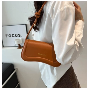 Detail of caramel brown leather shoulder bag with knotted strap and gold Miss mini text