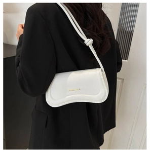 Detail of white baguette bag with curved wave bottom and golden Miss mini lettering