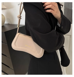 Detail of light beige leather underarm bag featuring Miss mini gold logo and knotted strap