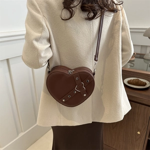 Bruine hartvormige crossbodytas met zilveren klinknagels en dunne riem op model
