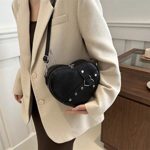 Modieuze zwarte hartvormige crossbodytas met zilveren studs op een elegante modeloutfit