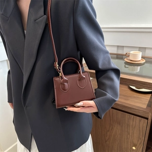 Minimalist dark brown crossbody bag with gold hardware and adjustable strap on model