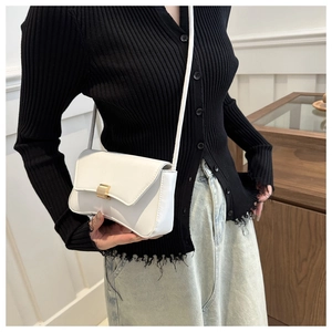 Detail of a white minimalist shoulder bag with a square gold metallic buckle clasp