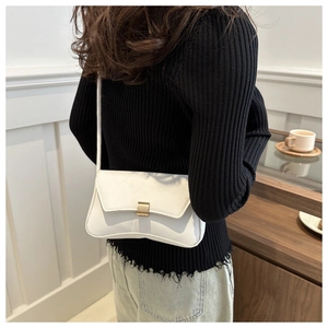 Detailed view of elegant white leather shoulder bag with a gold rectangular metal buckle