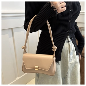 Detail of beige faux leather baguette bag showing golden buckle and hand-knotted strap