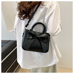 Fashionable black crossbody bag featuring a large decorative bow and a round top handle