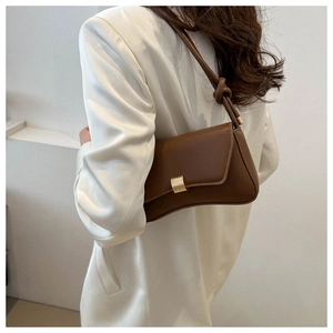 Close-up of brown leather shoulder bag with golden buckle and knot detail on the strap