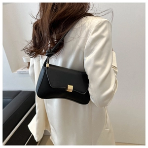 Detail of black leather bag with gold buckle and decorative knot on shoulder strap