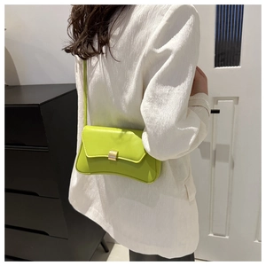 Detail of neon green rectangular underarm bag with gold metallic buckle on a model