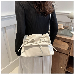 Close-up of cream pleated shoulder bag with bow details and soft PU leather texture
