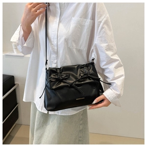 Close-up of black pleated PU shoulder bag with bow detail and Fashion text