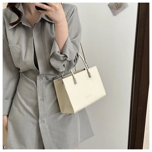 Spiegelselfie einer cremefarbenen Tasche mit FASHION-Prägung und silbernen Details