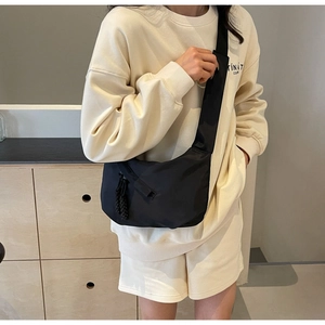 Close-up of black moon bag with woven zipper pull on model in casual indoor setting