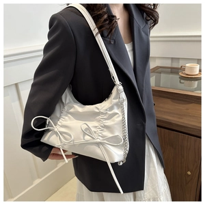 Detailed close-up of white pleated bow shoulder bag with silver chain and elegant leather straps