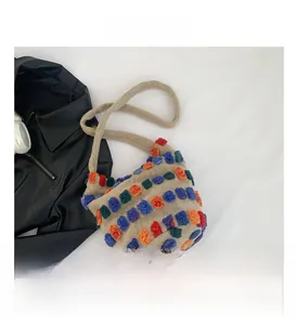 Detailed view of beige fuzzy knit bucket bag with vibrant multi-color pom-pom accents
