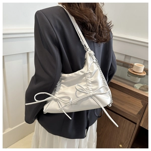 Detailed view of a white pleated shoulder bag with decorative bows and chain strap