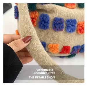Macro shot of stylish thick knitted shoulder strap with colorful 3D pom-poms on bucket bag