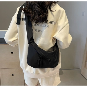 Détail du sac croissant en nylon noir avec bandoulière large et tirette tressée