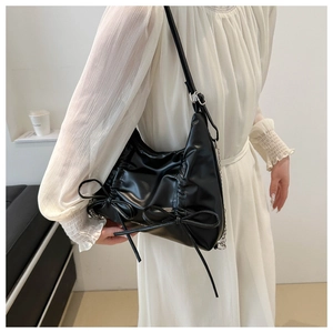 Detail view of black PU leather hobo bag featuring pleated texture and bow accents