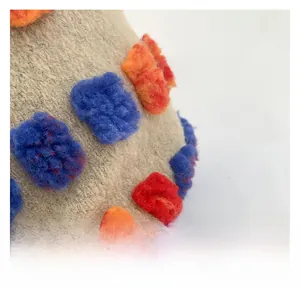 Close-up of textured knit fabric with vibrant colorful pom-poms on large tote bag