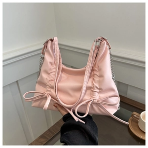 Detail of pink bow handbag featuring glossy finish and elegant silver metal chain strap