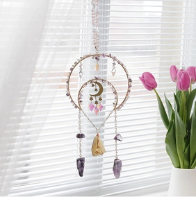 Detail of amethyst moon and star suncatcher with crystal prisms near a window