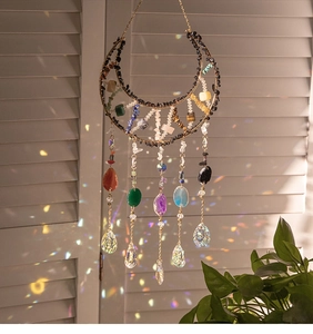 Detail of moon suncatcher with crystals casting rainbow light on white shutters