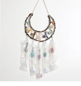 Macro shot of boho crescent moon suncatcher featuring raw crystals and gold metal frame