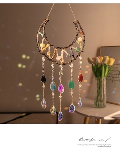Detail of moon-shaped suncatcher with natural raw stones and crystal prism rainbows