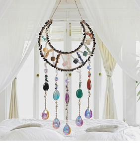Detailed shot of moon-shaped suncatcher with natural stones and hanging crystal prisms