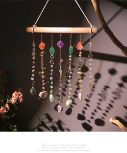 Close-up of bohemian crystal suncatcher with natural raw stones and agate slices on wood