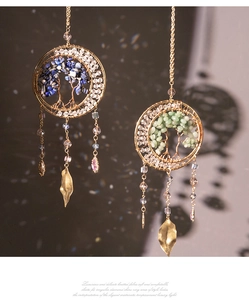 Detailed view of handmade tree of life pendants with crystals and golden metal leaves