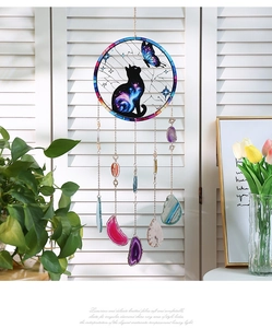 Detailed view of suncatcher with agate slices and cat butterfly frame against blinds