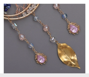 Macro shot of Tree of Life crystal pendant with gold wire and pink gemstone charms