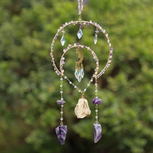 Handmade amethyst sun catcher wind chime with golden moon and crystals hanging outdoors