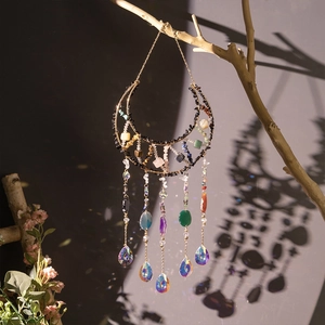 Moon-shaped suncatcher with natural crystals and obsidian stones on a gold metal frame