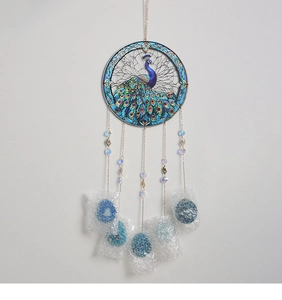 Detail of peacock suncatcher featuring vibrant blue stained glass and beaded metal chains