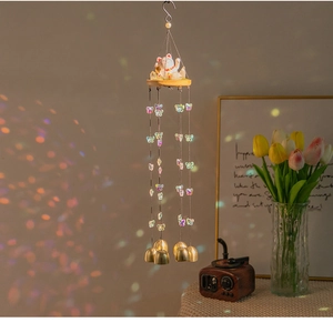 Detail of maneki-neko wind chime with butterfly charms and four copper bells hanging indoors
