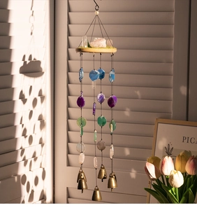 Detailed view of bohemian agate wind chime with crystal slices and brass bells on a sunny porch