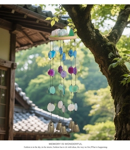 Close-up of natural agate wind chime with wooden base and bronze bell outdoors