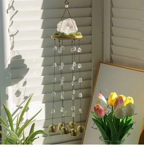 Détail d'un carillon en cristal avec cloches en laiton et décor de succulentes au soleil